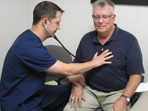 This is a picture of a doctor listening to a a elderly males breath sounds